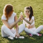 Caucasian mother and daughter in sportswear sharing a bonding moment outdoors.