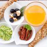 A delicious and nutritious breakfast featuring juice, bread, and fresh toppings on a white plate.